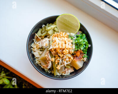 Shred Huhn instant Nudeln mit Knoblauch frittierte. Chili Pulver, Zitrone, Frühlingszwiebel und heiße Suppe mit Gewürzen in eine Schüssel am weißen Tisch Stockfoto