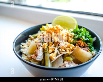 Shred Huhn instant Nudeln mit Knoblauch frittierte. Chili Pulver, Zitrone, Frühlingszwiebel und heiße Suppe mit Gewürzen in eine Schüssel am weißen Tisch Stockfoto