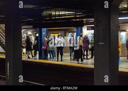 Langmut Wochenende u-bahn Mitfahrer amüsieren sich auf ihren Smartphones, wie sie für einen Zug an der Broadway-Lafayette Street Station in der New Yorker U-Bahn am Sonntag warten, 24. Februar 2019. (Â© Richard B. Levine) Stockfoto