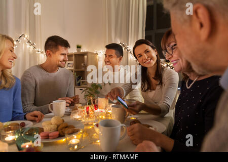 Glückliche Familie mit Smartphone bei Tea Party zu Hause Stockfoto