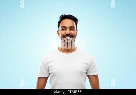 Lächelnden jungen indischen Mann über blauer Hintergrund Stockfoto