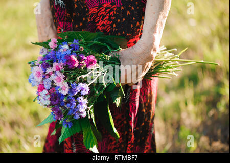 80-jährige Frau mit einem Blumenstrauß in der Hand. Stockfoto