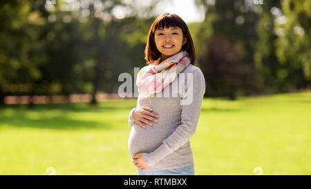 Glücklich schwanger asiatische Frau im Park Stockfoto
