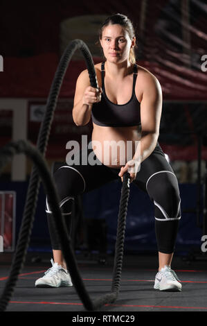 Schwangere junge Frau tun crossfit Übungen mit schwarzen Seile Stockfoto