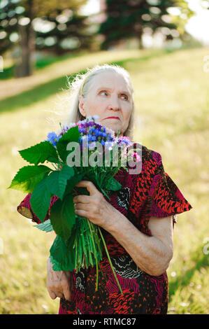 80-jährige Frau mit einem Blumenstrauß in der Hand. Stockfoto