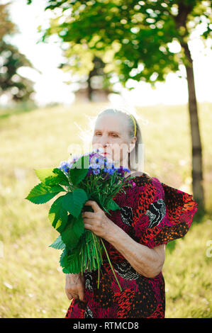 80-jährige Frau mit einem Blumenstrauß in der Hand. Stockfoto