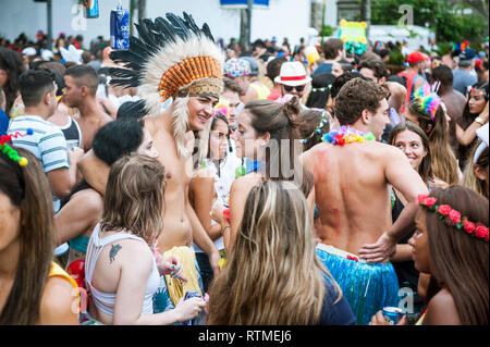 RIO DE JANEIRO - 28. FEBRUAR 2017: Eine junge brasilianische Mann kleidet sich in traditionellen Native American tribal Kopfbedeckung zu einem Karneval Straßenfest. Stockfoto