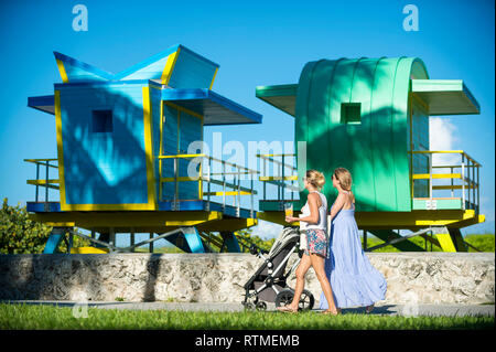 MIAMI - Juli 2017: Junge Frauen mit einem Kinderwagen entlang der Promenade von Miami Beach Vergangenheit Leuchtendbunten neu Rettungstürme gebaut. Stockfoto