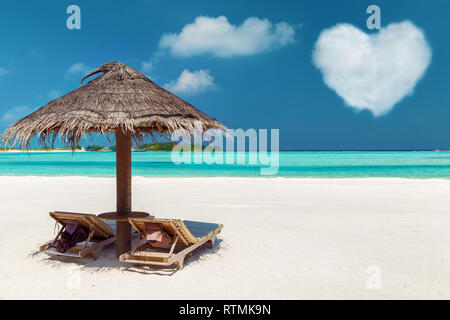 Zwei Sonnenliegen unter Palapa auf Malediven Beach Stockfoto