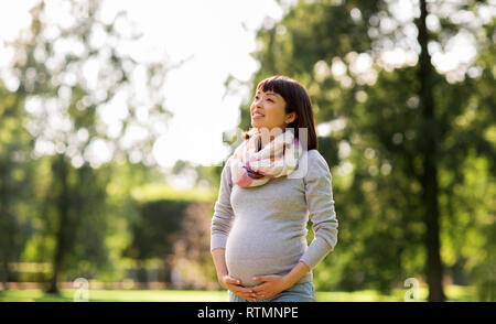 Glücklich schwanger asiatische Frau im Park Stockfoto
