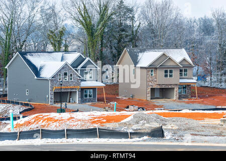Horizontale Schuß von zwei neuen 2-stöckigen Häuser im Bau im Winter. Schnee ist auf dem Boden und auf den Dächern. Stockfoto