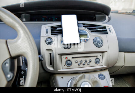 Smartphone in einem Auto für Navigieren oder GPS. Das Fahren eines Autos mit Smartphone im Halter. Handy isoliert weißer Bildschirm. Leer, leeres Bild. Kopieren Sie spa Stockfoto