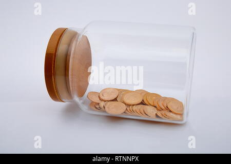 Blick auf die goldenen Münzen im Glas, auf weißem Hintergrund. Stockfoto