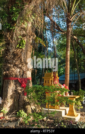 Geist Haus in Thailand mit Blumengirlanden in der Nähe der Großen Baum Stockfoto