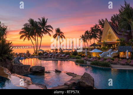 Schöne Aussicht auf den Sonnenuntergang mit Palmen in Schwimmbad in Luxury Island Resort in Thailand widerspiegelt Stockfoto