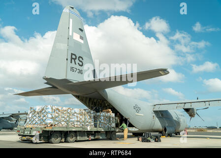 Us-Betrieb Fremdfirmen laden Sie eine C-130J Hercules, zugeordnet zu den 75th Expeditionary Airlift Squadron (EAS), mit Paletten von Wasser im Camp Lemonnier, Dschibuti, Jan. 12, 2019. 75 EAS unterstützt Combined Joint Task Force - Horn von Afrika mit medizinische Evakuierungen, Katastrophenhilfe, humanitäre und airdrop Operationen. (U.S. Air Force Foto von Tech. Sgt. Thomas Grimes) Stockfoto