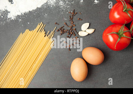 Teigwaren mit Tomaten, Knoblauch und Eier, Essen closeup auf schwarzen Holztisch Hintergrund, essen Konzept Stockfoto