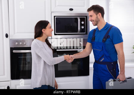 Lächelnden jungen männlichen Serviceman Händeschütteln mit Frau Stockfoto