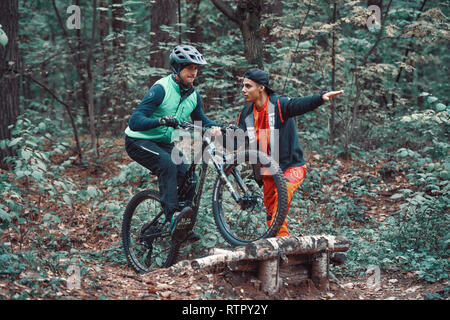 Moskau, Russland - Nov, 2018: MTB-Lehrer helfen Reiter lernen, Fahrrad zu fahren. Lehre ein Reiter, ein Fahrrad auf einem Trail zu fahren. Zwei Freunde haben Spaß in der Natu Stockfoto