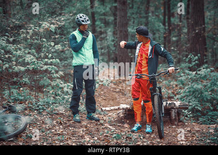 Moskau, Russland - Nov, 2018: MTB-Lehrer helfen Reiter lernen, Fahrrad zu fahren. Lehre ein Reiter, ein Fahrrad auf einem Trail zu fahren. Zwei Freunde haben Spaß in der Natu Stockfoto