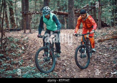 Moskau, Russland - Nov, 2018: MTB-Lehrer helfen Reiter lernen, Fahrrad zu fahren. Lehre ein Reiter, ein Fahrrad auf einem Trail zu fahren. Zwei Freunde haben Spaß in der Natu Stockfoto