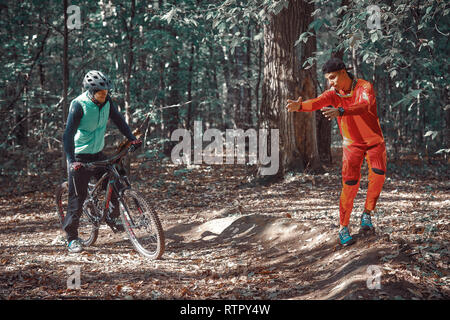 Moskau, Russland - Nov, 2018: MTB-Lehrer helfen Reiter lernen, Fahrrad zu fahren. Lehre ein Reiter, ein Fahrrad auf einem Trail zu fahren. Zwei Freunde haben Spaß in der Natu Stockfoto