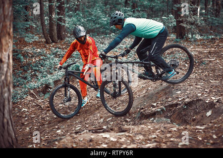 Moskau, Russland - Nov, 2018: MTB-Lehrer helfen Reiter lernen, Fahrrad zu fahren. Lehre ein Reiter, ein Fahrrad auf einem Trail zu fahren. Zwei Freunde haben Spaß in der Natu Stockfoto