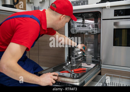 Home Appliance Maintenance - reparateur Reparatur Geschirrspüler in der Küche Stockfoto