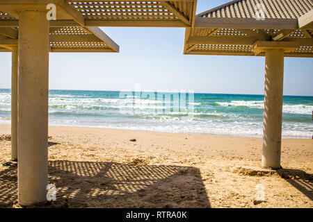 Strand von Tel Aviv, Israel. Sonniges Wetter mit strahlend blauem Himmel und schönen Schatten form Stein Strand Sonnenschirme. Stockfoto