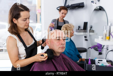 Nach kahl männlichen Klienten empfangen von Dienst, der von Professional Friseur im Salon Stockfoto