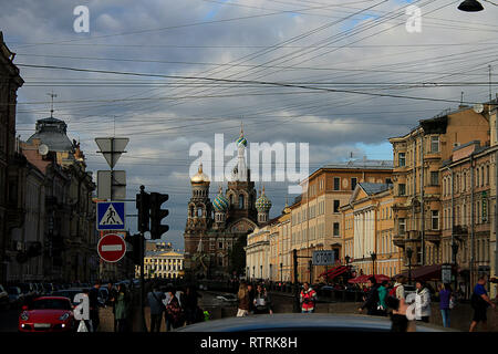 Kirche des Erlösers auf Blut in St. Petersburg von der Straße aus der Entfernung mit Menschen und Verkehrszeichen und eine Wolke aus Himmel gesehen. Stockfoto