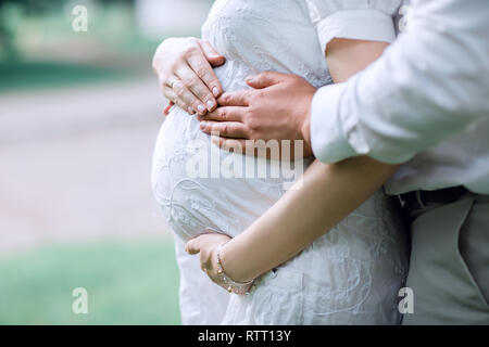 Zugeschnittenes Bild des Ehemannes holding Bauch seiner schwangeren Frau Stockfoto