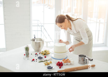 Happy girl Verbreitung der frostigen auf der Torte, Foto schliessen. kopieren. Stockfoto