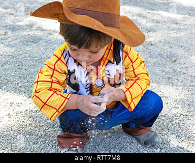 Kleines Kind, Kind, Kinder tragen Woody Toy Story Kostüm spielen auf dem Boden mit dem Schmutz und Sand, die schmutzigen Hände. Kindheit Kreativität in Spanien im Jahr 2019. Stockfoto