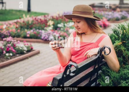 Jugendlicher Mädchen verwendet Ihr Telefon im Park sitzt auf der Bank Stockfoto