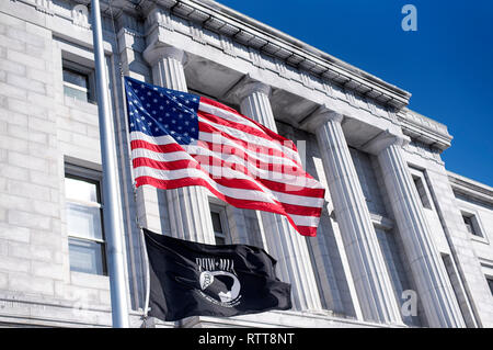 Die amerikanische und die POW flags Flying zum halben Personal vor dem Cumberland County Courthouse in Portland Maine an einem sonnigen blauen Himmel. Stockfoto