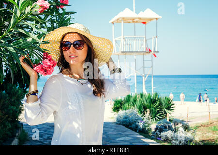 Junge hübsche Frau, die zu Fuß auf den Strand von der Rhododendron Blumen Stockfoto