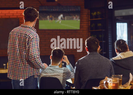 Junge Menschen, Fußball im Fernsehen in der Bar. Stockfoto