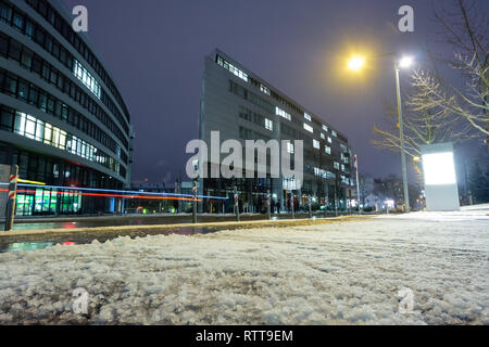 Schnee im Winter auf einem Bürgersteig und verschwommen Auto leuchtet bei einer Road Stockfoto