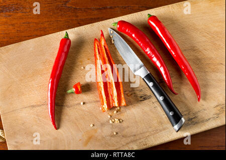 Entkörnen Red Hot Chili Peppers auf einem Schneidebrett mit Messer Stockfoto
