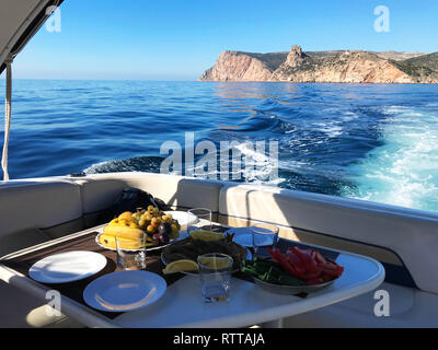 Restaurant am Meer vor blauem Wasser und Yacht Hafen der Ägäischen Küste auf Cesme. Marmortisch mit Platte von Rindfleisch Häppchen essen. Kopieren Sie Platz für Stockfoto