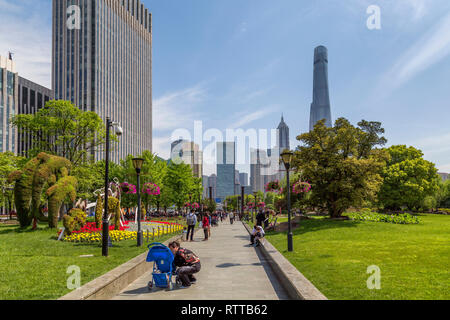 Die Menschen genießen einen Spaziergang durch Lujiazui zentralen Grönland, ein Park in der Pudong New Area Shanghai. Wolkenkratzer kann im Hintergrund gesehen werden. Stockfoto