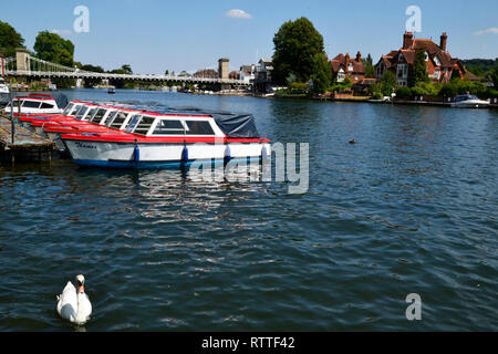 Mieten Sie Boote am Ufer der Themse in Marlow, Buckinghamshire, England, UK. Marlow Bridge in der Ferne. Stockfoto