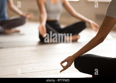 Gruppe von Menschen üben Yoga Lektion mit Kursleiter, Ardha Padmasana Stockfoto