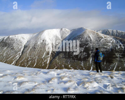 Einsame männliche Wanderer im Schnee mit Sattel Yorke im Hintergrund auf dem Weg zur schottischen Berge Corbett Hart fiel, Moffat Dale, Scottish Borders. Stockfoto