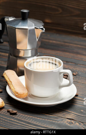 Tasse Kaffee mit Kaffeemaschine auf hölzernen Hintergrund Stockfoto