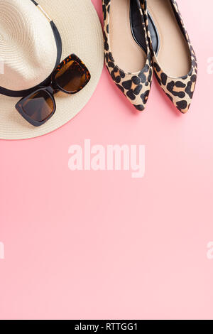 Stroh Hut, Sonnenbrille und trendigen Leopardenmuster Schuhe auf Pastell rosa Hintergrund, Sommer Fashion Concept. Ansicht von oben, selektiver Fokus Stockfoto