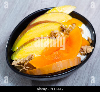 Kürbisscheiben Backen im Ofen, Mango. Haferflocken, Schlagsahne, getrocknete Früchte auf einem Teller mit Kürbis und Mango Stockfoto