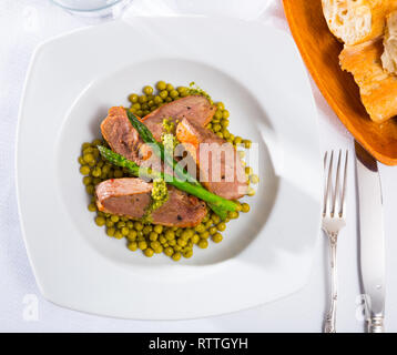 Leckere gegrillte Entenbrust mit grünen Erbsen, Spargel und Pesto Sauce serviert. Stockfoto