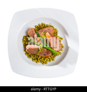 Leckere gegrillte Entenbrust mit grünen Erbsen, Spargel und Pesto Sauce serviert. Auf weissem Hintergrund Stockfoto